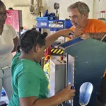 A student from the Newfield Primary School adding bottlecaps to the grinder