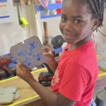 A student from the Newfield Primary School holding up a mold of upcycled plastic keychains
