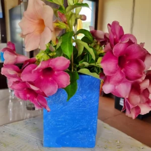 A bouquet of fresh flowers in a Large square pot made from bottlecaps