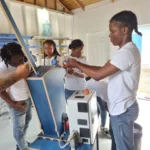 Workshop assistants putting bottlecaps in the Granulator to be shredded